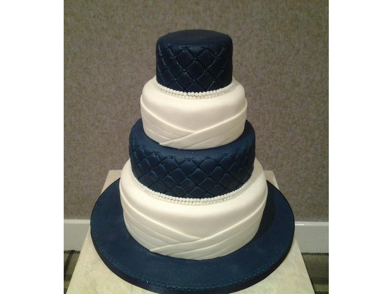 Simplistic royal blue and white 4 tier wedding cake with pearls. Made in vaniila and chocolate with orange sponges and carrot cake.